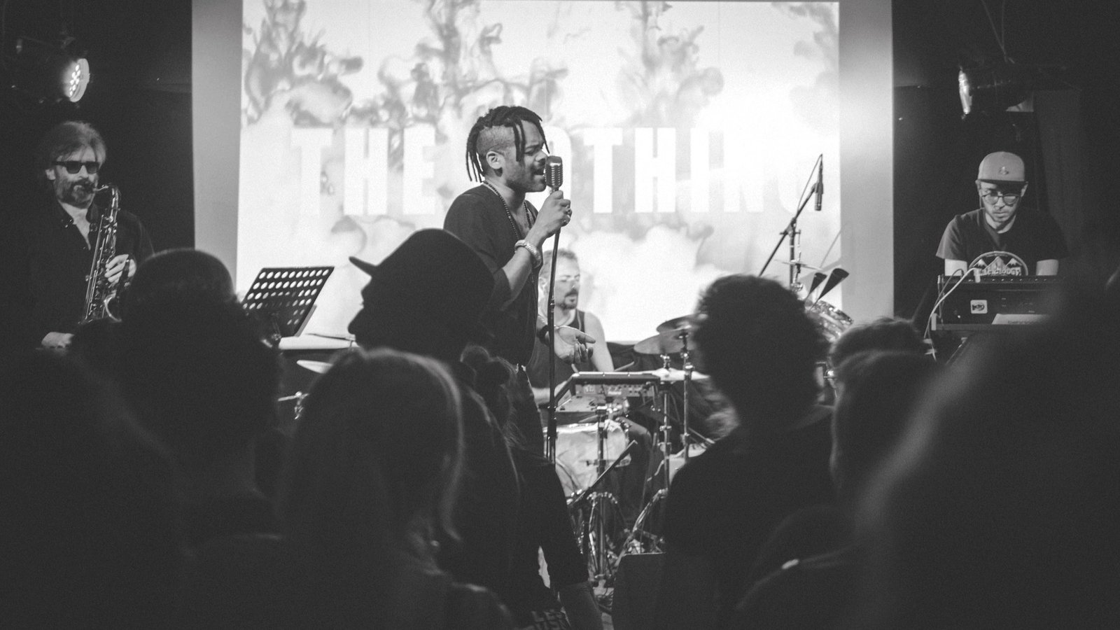 The Nothing sur scène, le wordmark projeté en fond, public au premier plan
